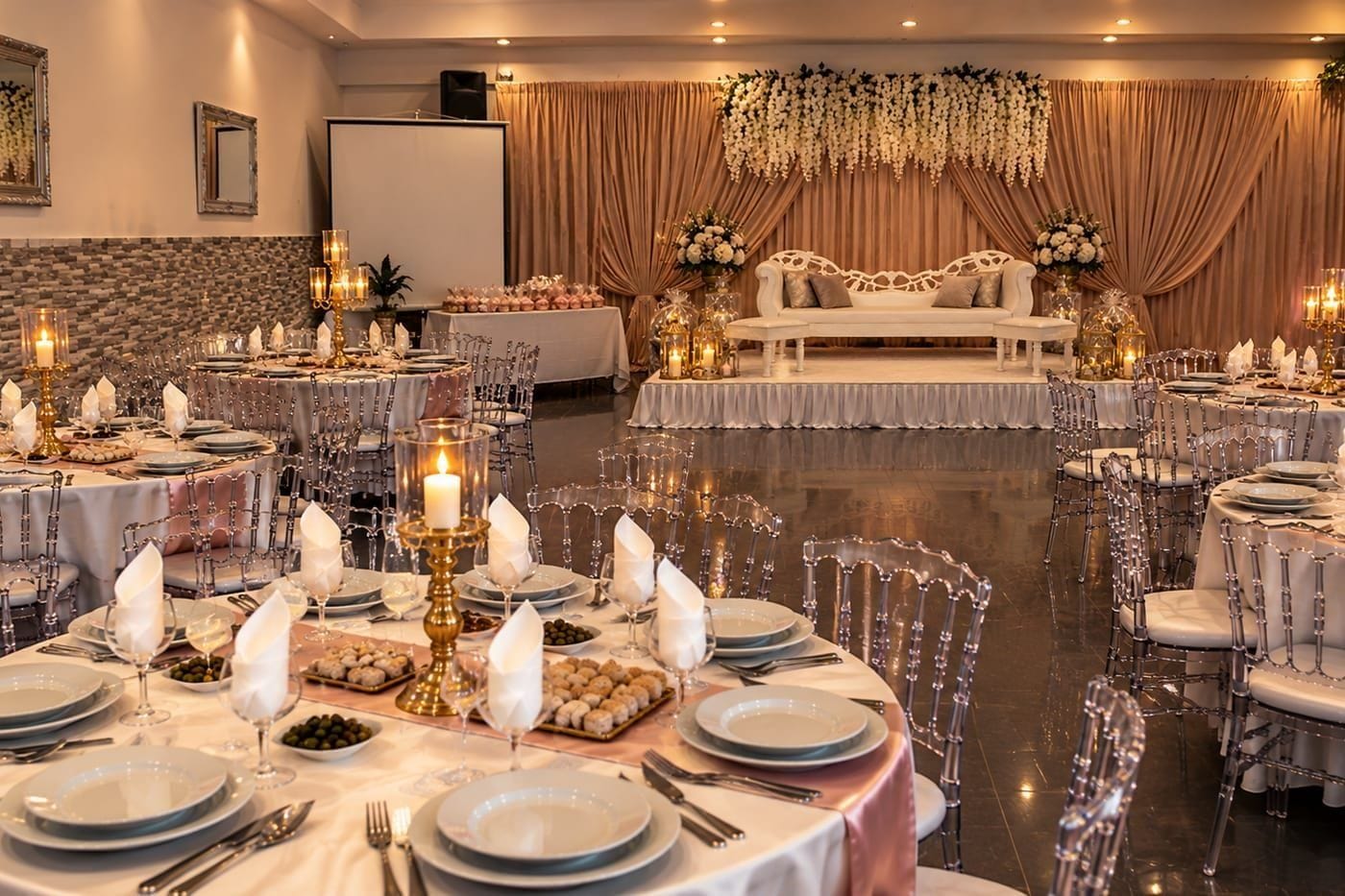 La salle de réception dressée un soir de fête, estrade et tables rondes